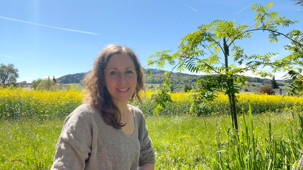 Jeannine Maurer sitzt vor dem blühenden Rapsfeld