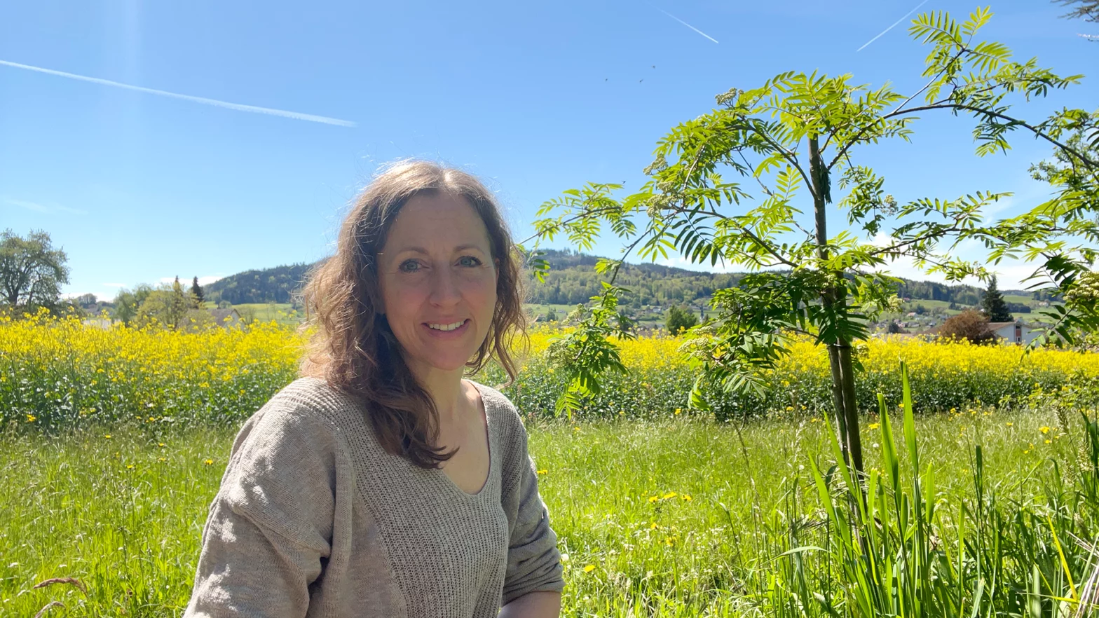 Jeannine Maurer sitzt vor dem blühenden Rapsfeld